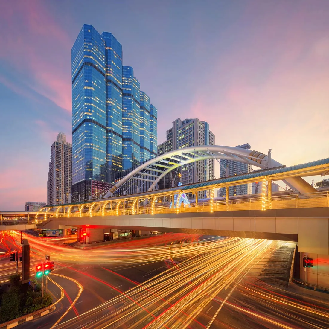 City traffic drawing light trails past a skyline at dusk